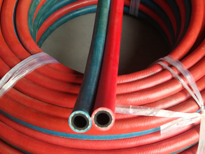 There is a roll of twin welding hoses packed by plastic rope.